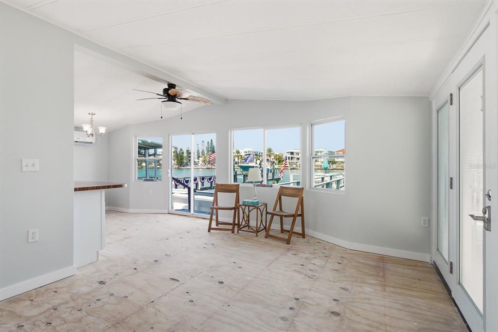 An interior room with unfinished plywood flooring, large windows, and a view of the water — 15010 113TH AVENUE UNIT 12, LARGO, FL