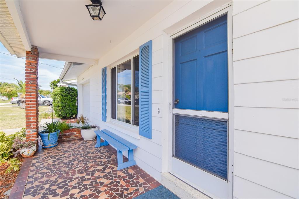 A covered porch features a mosaic tile floor, a blue bench, and a blue screen door — 11319 70TH TERRACE, SEMINOLE, FL