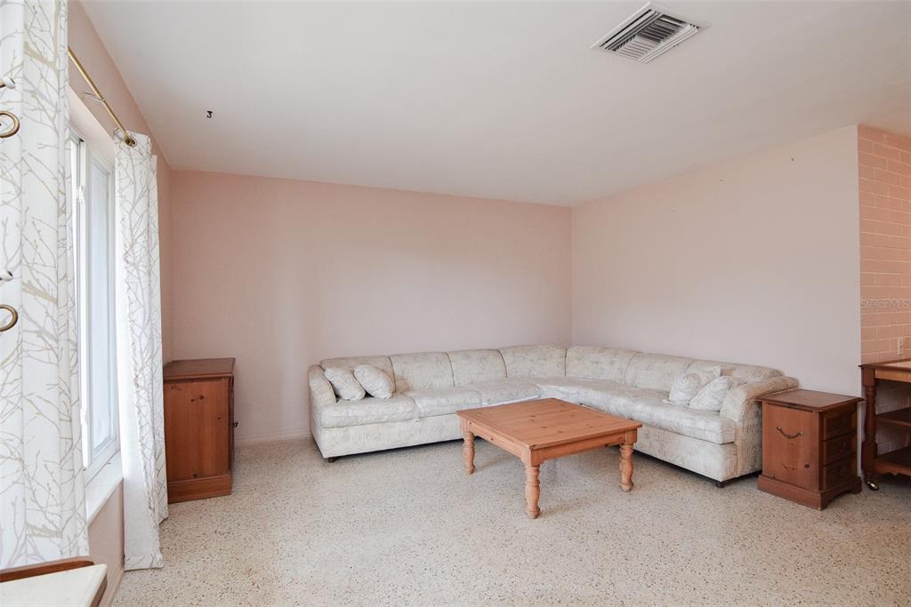 A living room features a beige sectional sofa, a wooden coffee table, and terrazzo flooring — 11319 70TH TERRACE, SEMINOLE, FL