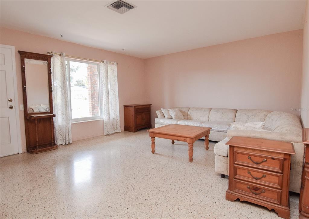 A living room features light-colored walls, terrazzo flooring, a sectional sofa, and wooden furniture — 11319 70TH TERRACE, SEMINOLE, FL