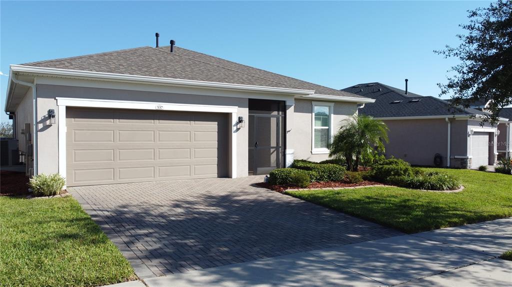 A single-story house with a beige stucco exterior, a two-car garage, and a paved driveway — 537 NARROW VIEW LANE, GROVELAND, FL