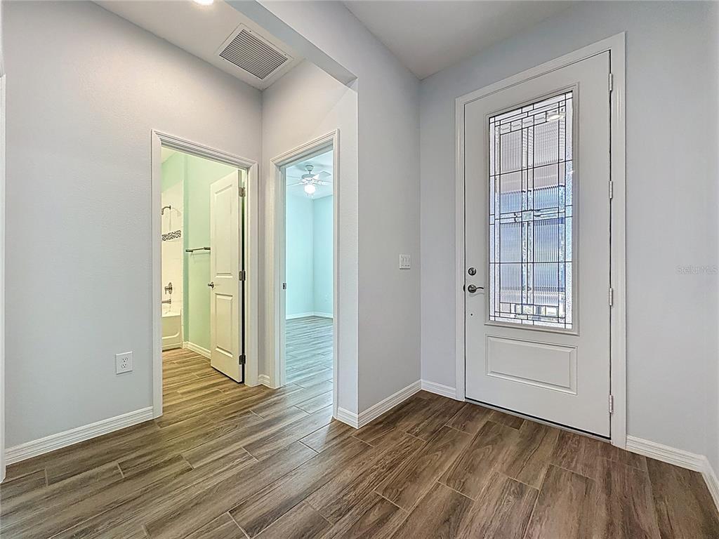 A hallway with wood-look tile flooring leads to a bathroom, a bedroom, and an entryway — 537 NARROW VIEW LANE, GROVELAND, FL