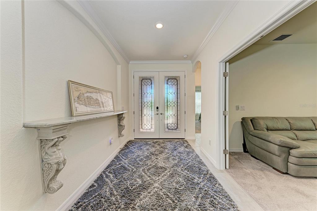 A foyer features a marble-topped console table with ornate brackets, a patterned rug, and double doors — 20706 BENISSIMO DRIVE, VENICE, FL