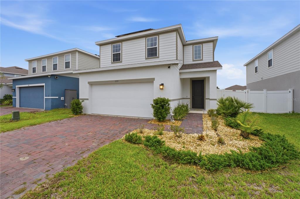 A two-story house with a white stucco facade, a two-car garage, and a brick driveway — 1715 OCEANIA AVENUE, DAVENPORT, FL