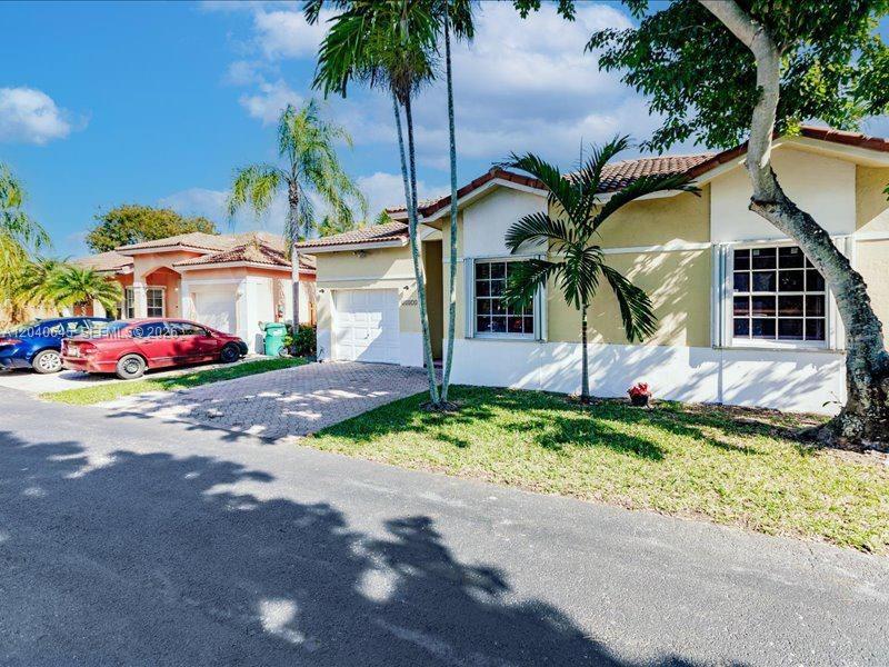 A single-story suburban house with a paved driveway, palm trees, and a red car parked — 21475 SW 90th Pl, Cutler Bay FL 33189, CUTLER BAY, FL