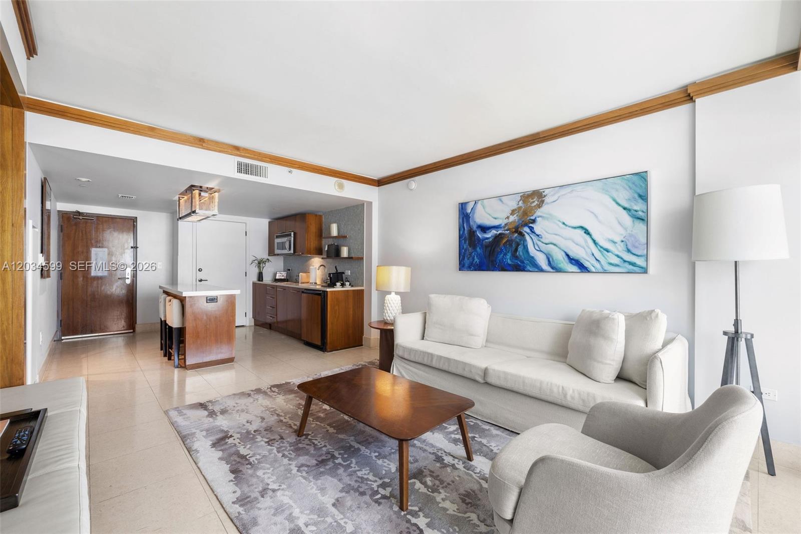 A living room features a white sofa, a coffee table, and an open kitchenette area — 6801 Collins Ave # 1010, Miami Beach FL 33141, MIAMI BEACH, FL
