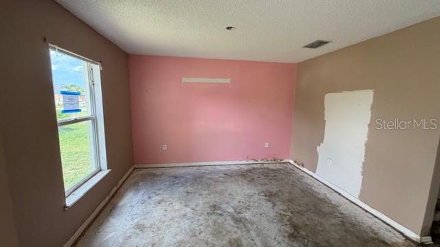 An empty room features pink and tan walls, a window, and a bare concrete floor — 464 MARTIGUES DRIVE, KISSIMMEE, FL