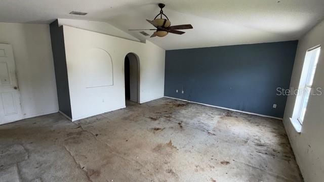 An empty room with a vaulted ceiling, a ceiling fan, and stained, worn carpeting — 464 MARTIGUES DRIVE, KISSIMMEE, FL