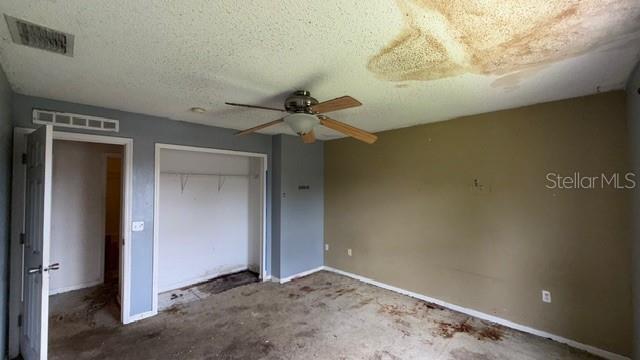 A bedroom with a ceiling fan, a closet, and significant water damage on the ceiling — 464 MARTIGUES DRIVE, KISSIMMEE, FL