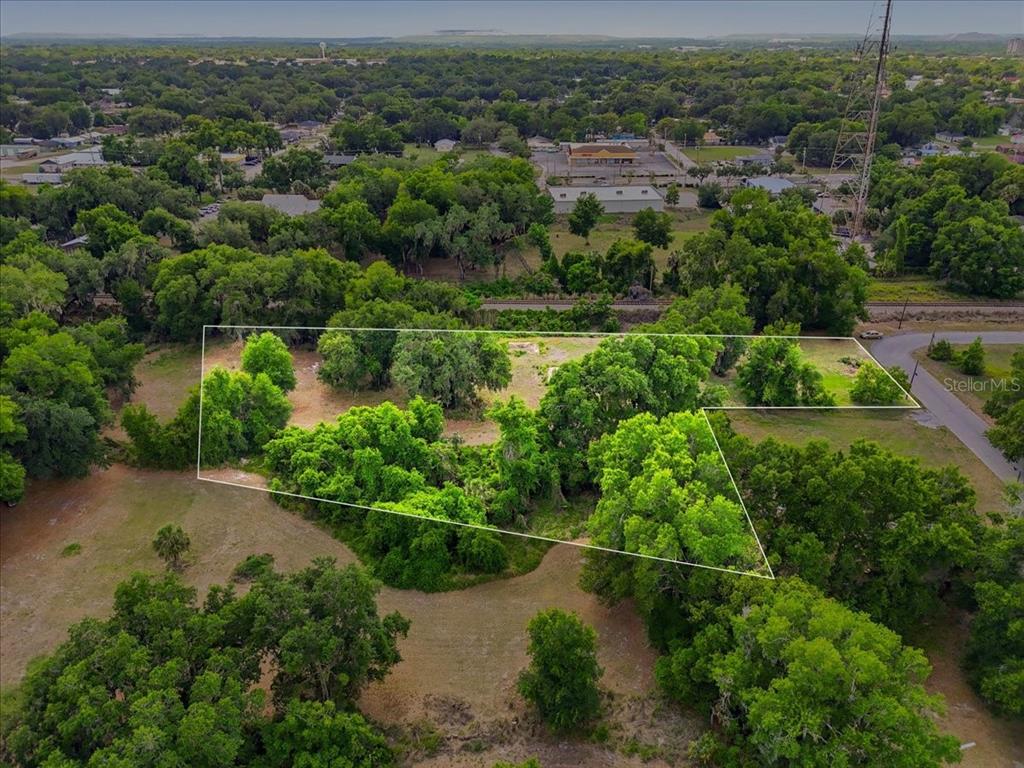 An aerial view shows a vacant, tree-covered lot outlined in white against a suburban landscape — 1705 MARSHALL STREET, BARTOW, FL