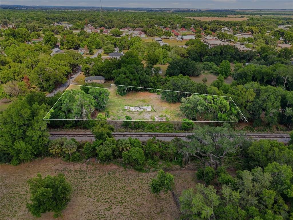 An aerial view shows a vacant, wooded lot with a concrete foundation near railroad tracks — 1705 MARSHALL STREET, BARTOW, FL