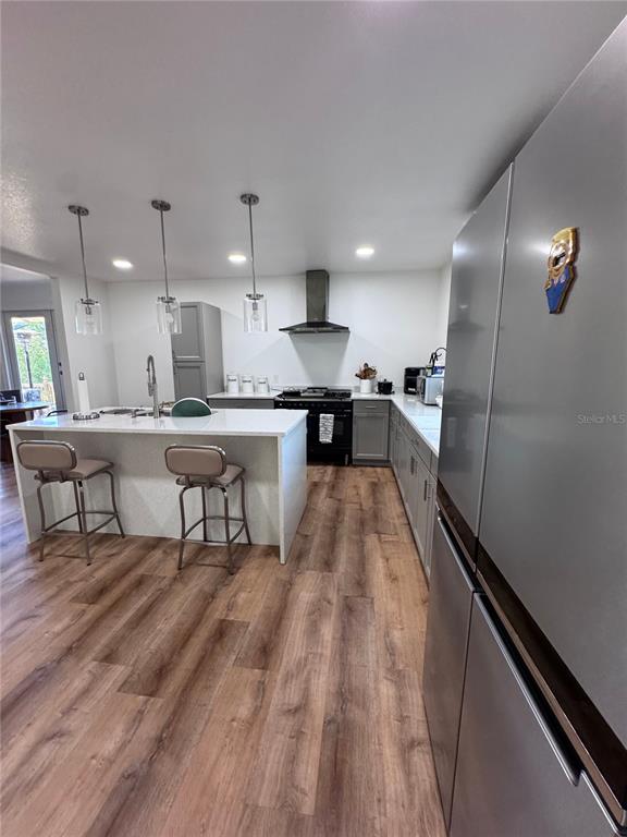 A modern kitchen features a white island with bar stools, stainless appliances, and wood flooring — 10731 LIBBY NUMBER 3 ROAD, CLERMONT, FL