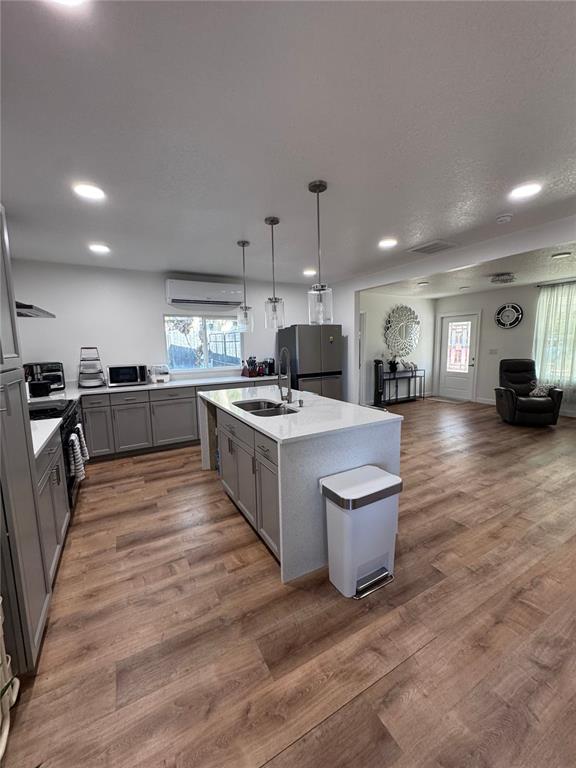 A modern kitchen features gray cabinetry, a white quartz island, and wood-look flooring — 10731 LIBBY NUMBER 3 ROAD, CLERMONT, FL