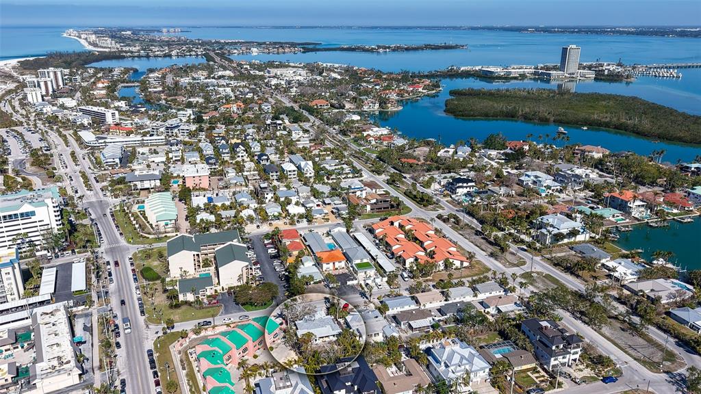 An aerial view shows a coastal neighborhood with a circled house near a turquoise bay — 132 HARRISON DRIVE, SARASOTA, FL