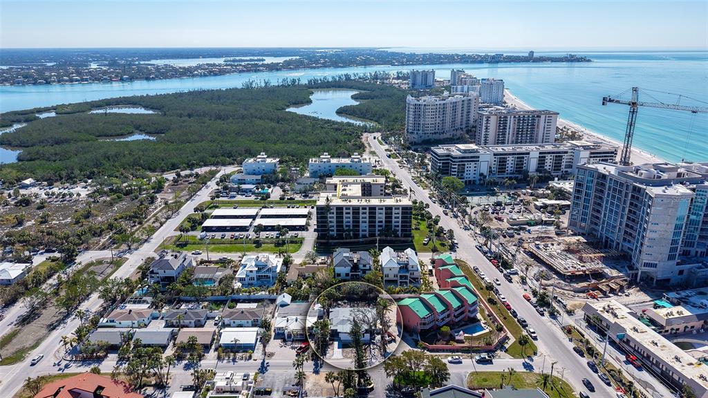 An aerial view shows a coastal neighborhood with a circled single-story house near the beach — 132 HARRISON DRIVE, SARASOTA, FL