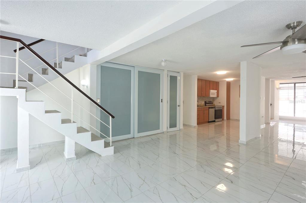 A bright, open-concept living area features white marble-look tile floors and a modern staircase — 632-5 AVE. SAN PATRICIO, GUAYNABO, PR