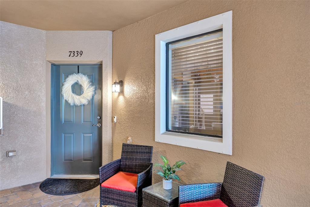A front entryway features a blue door with a wreath, two wicker chairs, and a window — 7339 SKYBIRD ROAD UNIT 7339, BRADENTON, FL