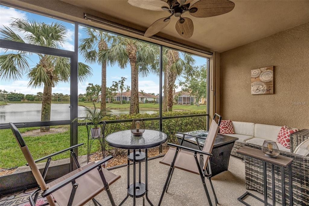 A screened-in patio features a small table, chairs, and a view of a pond — 7339 SKYBIRD ROAD UNIT 7339, BRADENTON, FL