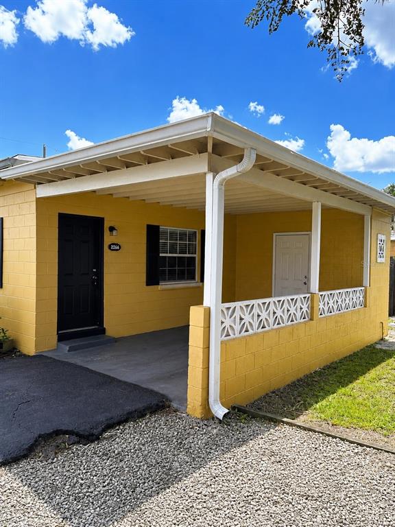 A yellow house features a covered carport, a black front door, and decorative concrete blocks — 2266 RAEFORD ROAD UNIT A6, ORLANDO, FL