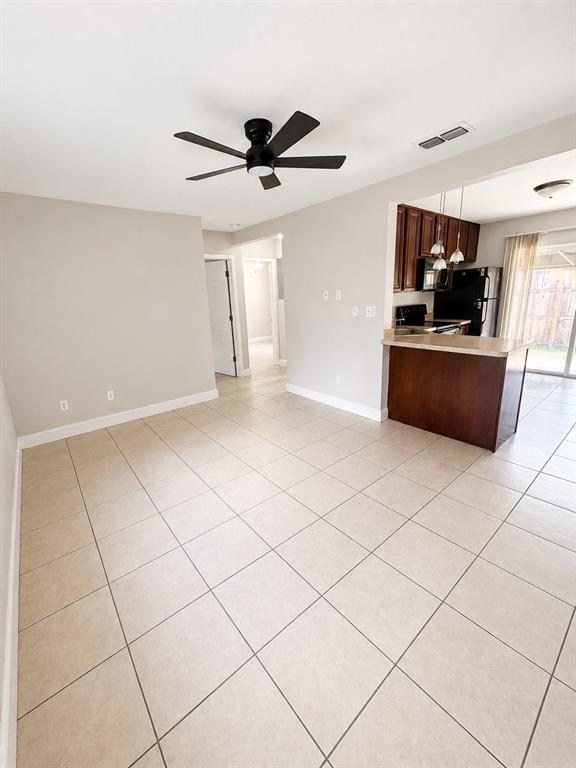 An open-concept living area features light tile flooring, a ceiling fan, and a kitchen peninsula — 2266 RAEFORD ROAD UNIT A6, ORLANDO, FL