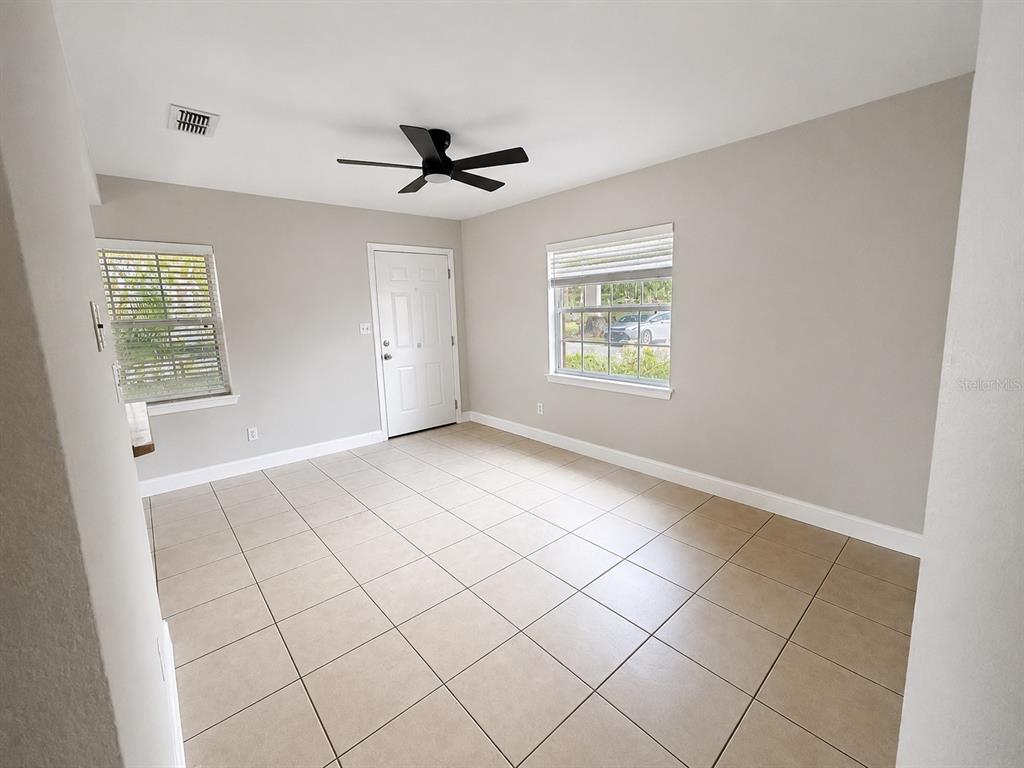 An empty room features beige tile flooring, light gray walls, a ceiling fan, and two windows — 2266 RAEFORD ROAD UNIT A6, ORLANDO, FL