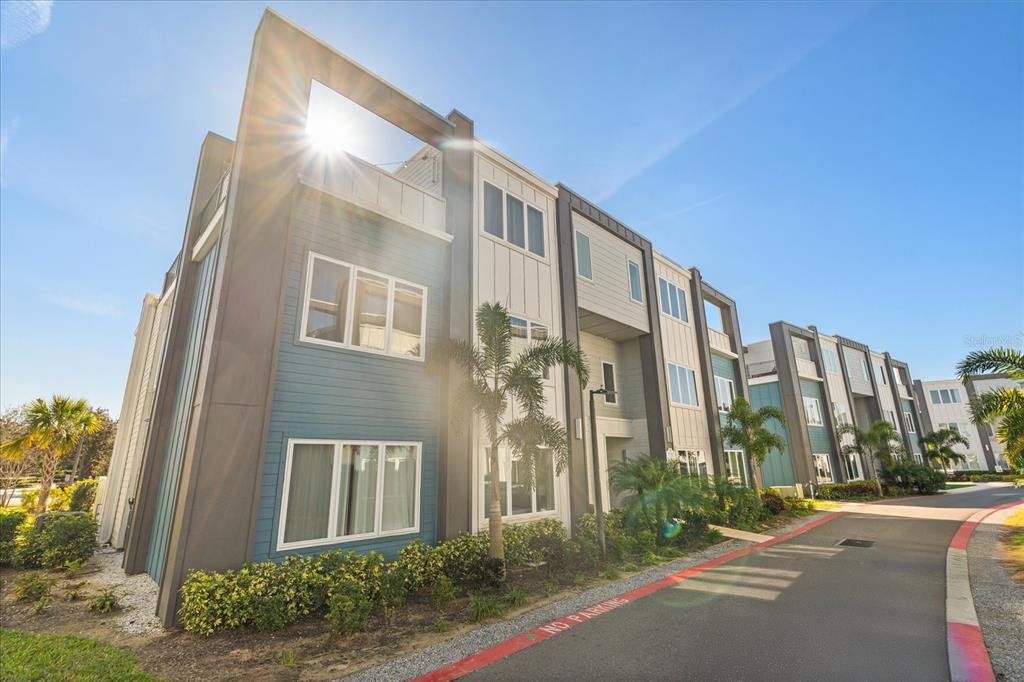 A low-angle exterior view of a modern multi-story apartment building with blue and white siding — 7760 SANDY RIDGE DRIVE UNIT 102, REUNION, FL
