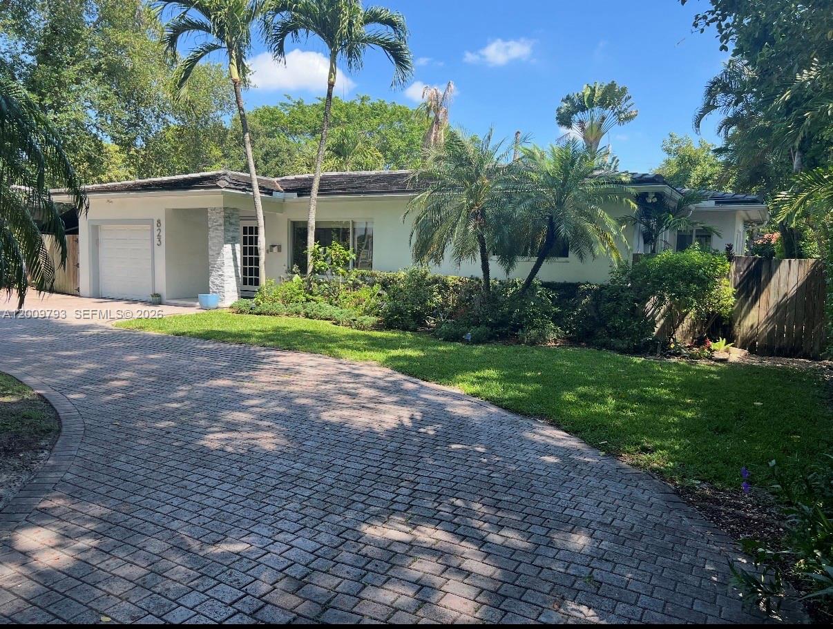 A single-story house with a paved driveway, palm trees, and a white garage door — 823 NE 107th St, Biscayne Park FL 33161, BISCAYNE PARK, FL