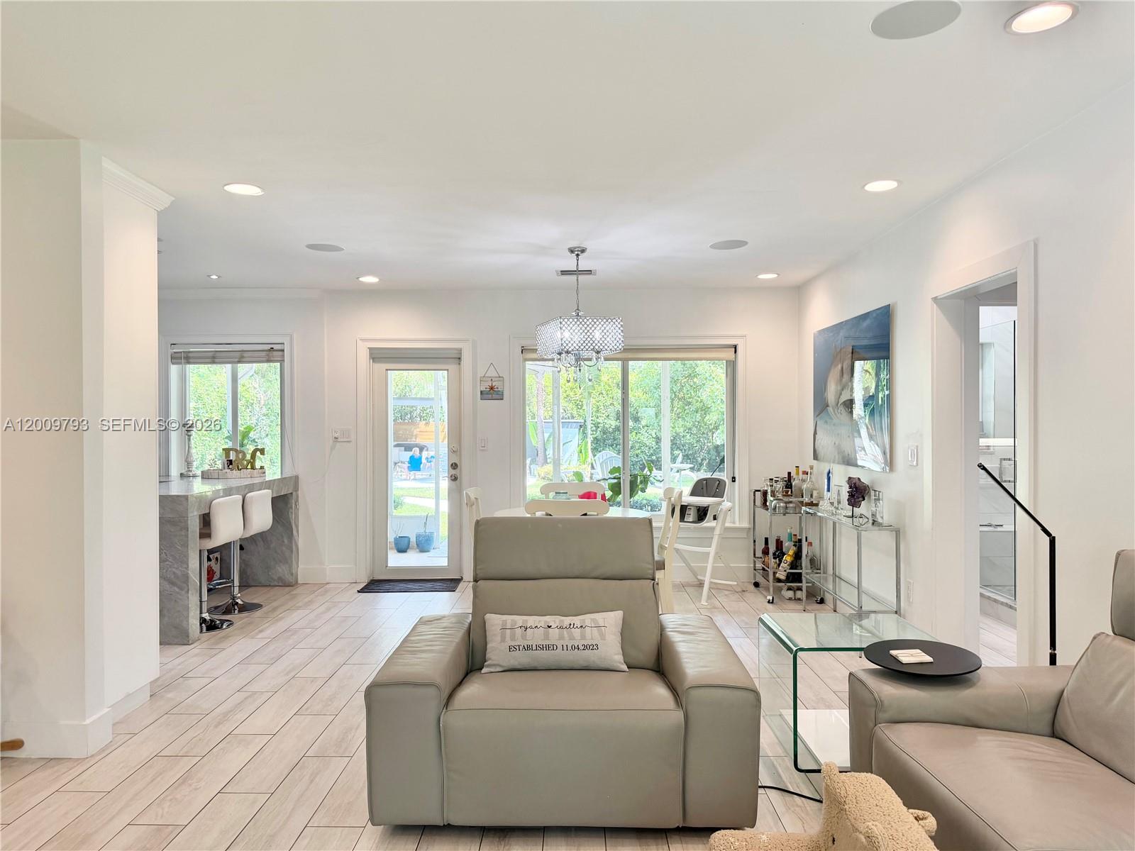 A living room with light tile floors, a gray leather armchair, and a dining area — 823 NE 107th St, Biscayne Park FL 33161, BISCAYNE PARK, FL
