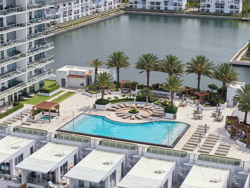 An aerial view of a swimming pool deck with lounge chairs, palm trees, and water — 5120 MARINA WAY UNIT 4408, TAMPA, FL