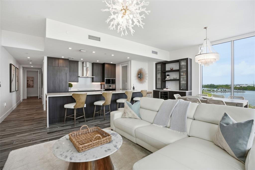 A modern open-concept living room and kitchen with dark cabinetry, white sofa, and water views — 5120 MARINA WAY UNIT 4408, TAMPA, FL