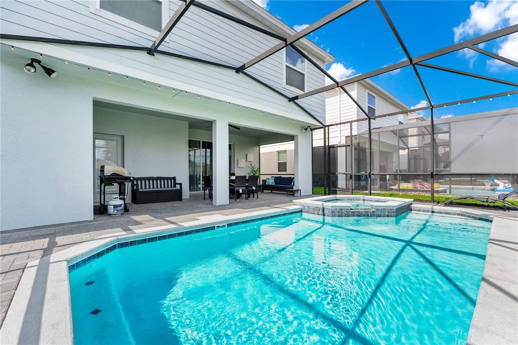A backyard features a swimming pool with an attached spa inside a screened-in patio area — 3883 LANA AVENUE, DAVENPORT, FL