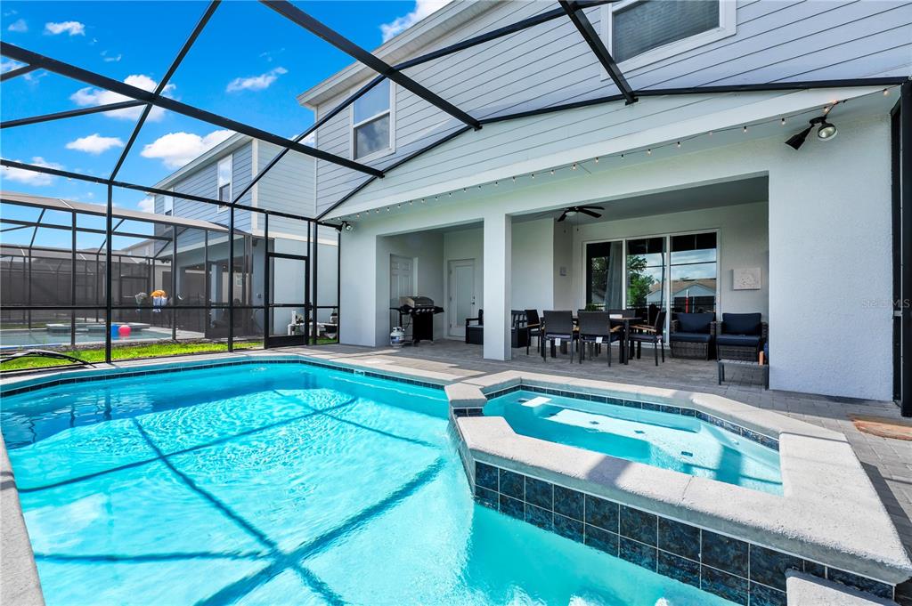 A screened-in patio features a swimming pool, a raised spa, and an outdoor dining area — 3883 LANA AVENUE, DAVENPORT, FL