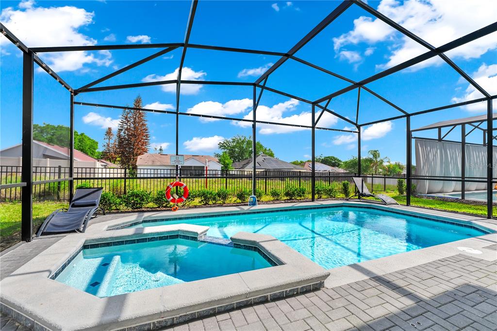 A screened-in swimming pool and attached hot tub sit on a paved patio — 3883 LANA AVENUE, DAVENPORT, FL