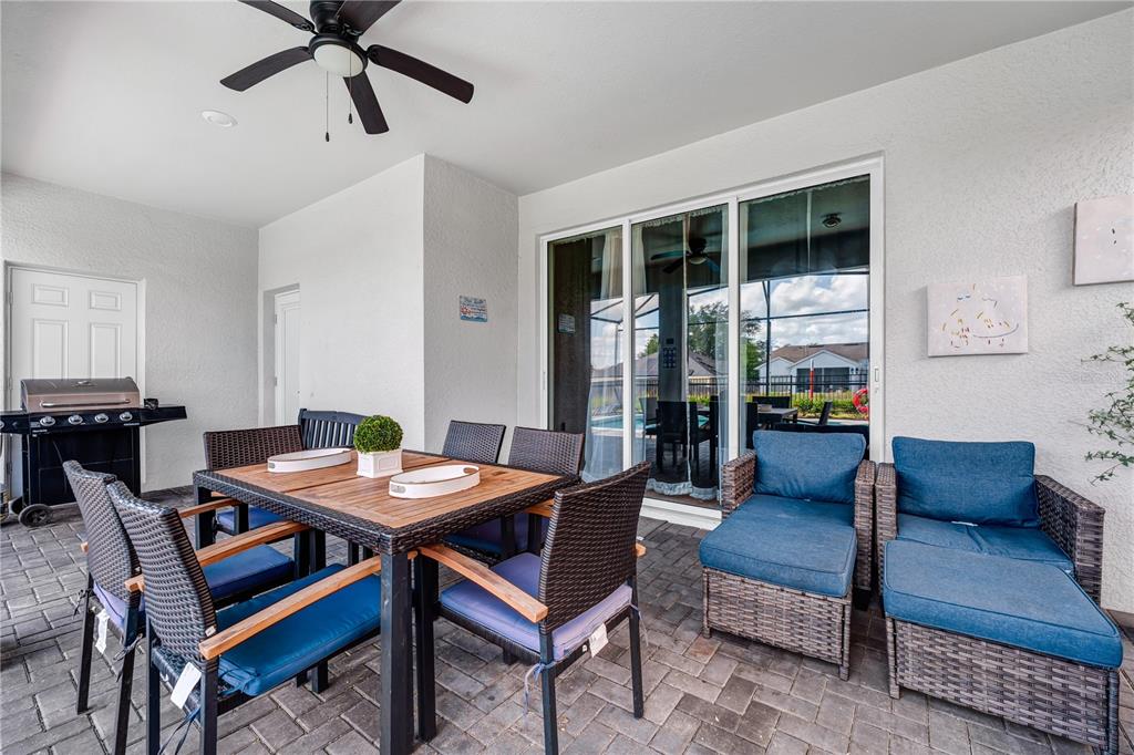 A covered patio features a dining set, lounge chairs, a grill, and sliding glass doors — 3883 LANA AVENUE, DAVENPORT, FL