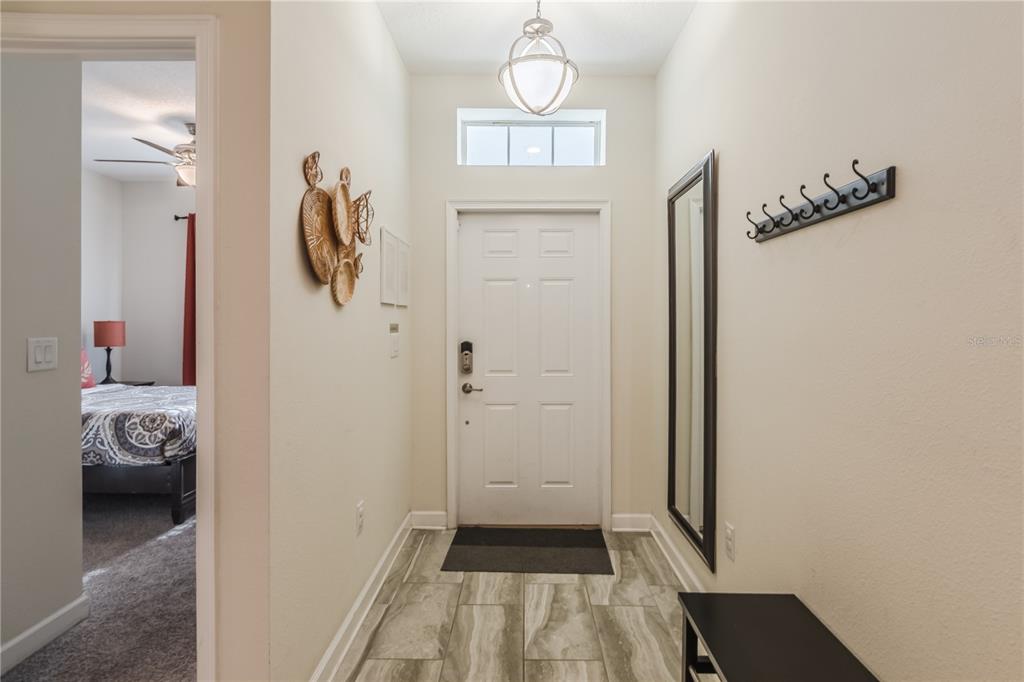 An entryway features a white front door, tile flooring, a wall mirror, and a coat rack — 1588 FLANGE DRIVE, DAVENPORT, FL