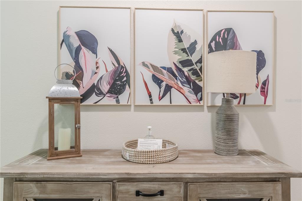 A wooden console table features a lantern, a woven tray, and a lamp beneath artwork — 1588 FLANGE DRIVE, DAVENPORT, FL
