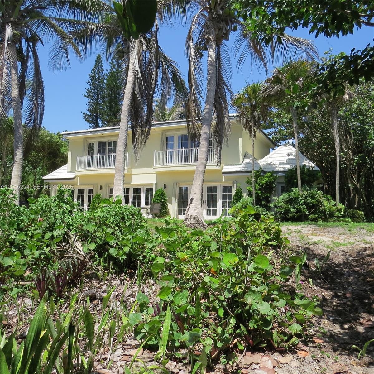 A two-story yellow house with balconies is surrounded by palm trees and lush vegetation — 404 S Beach Rd # 404, Jupiter Island FL 33455, JUPITER ISLAND, FL