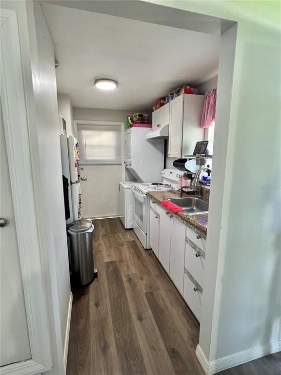 A galley kitchen features white cabinets, laminate countertops, a stainless steel sink, and white appliances — 1701 MONTECITO AVENUE, DELTONA, FL