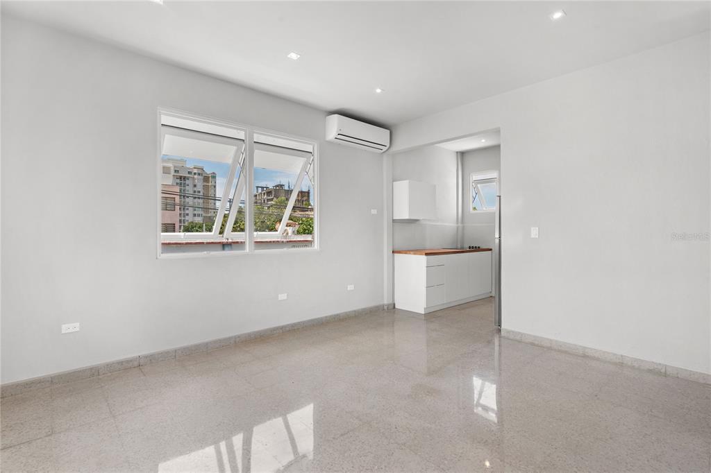 An interior view of a room with light-colored tile floors, white walls, and a kitchenette — 107 TAFT UNIT 5, SAN JUAN, PR