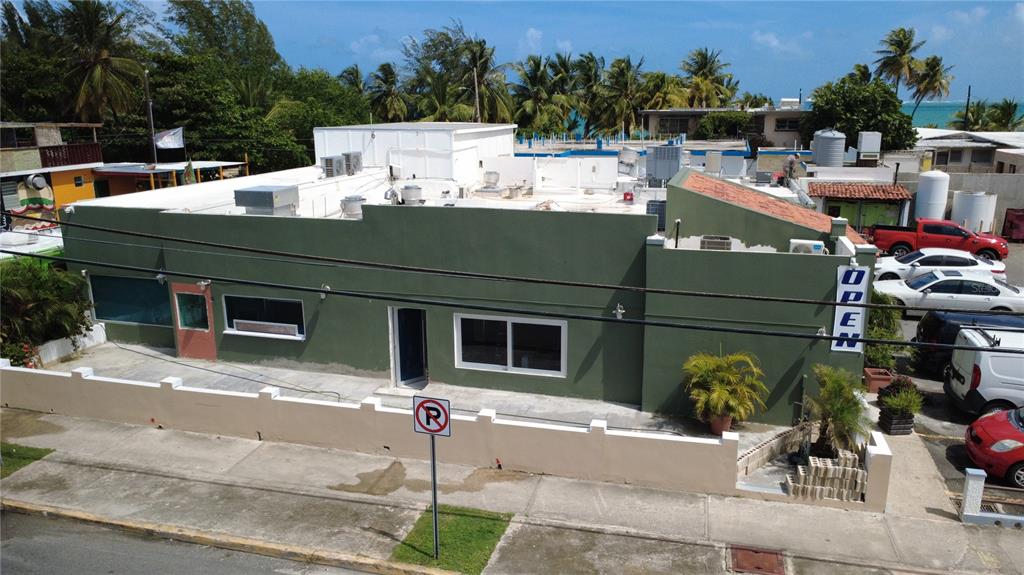 An aerial view shows a green commercial building with a parking lot and surrounding palm trees — 2475 LOÍZA STREET, SAN JUAN, PR