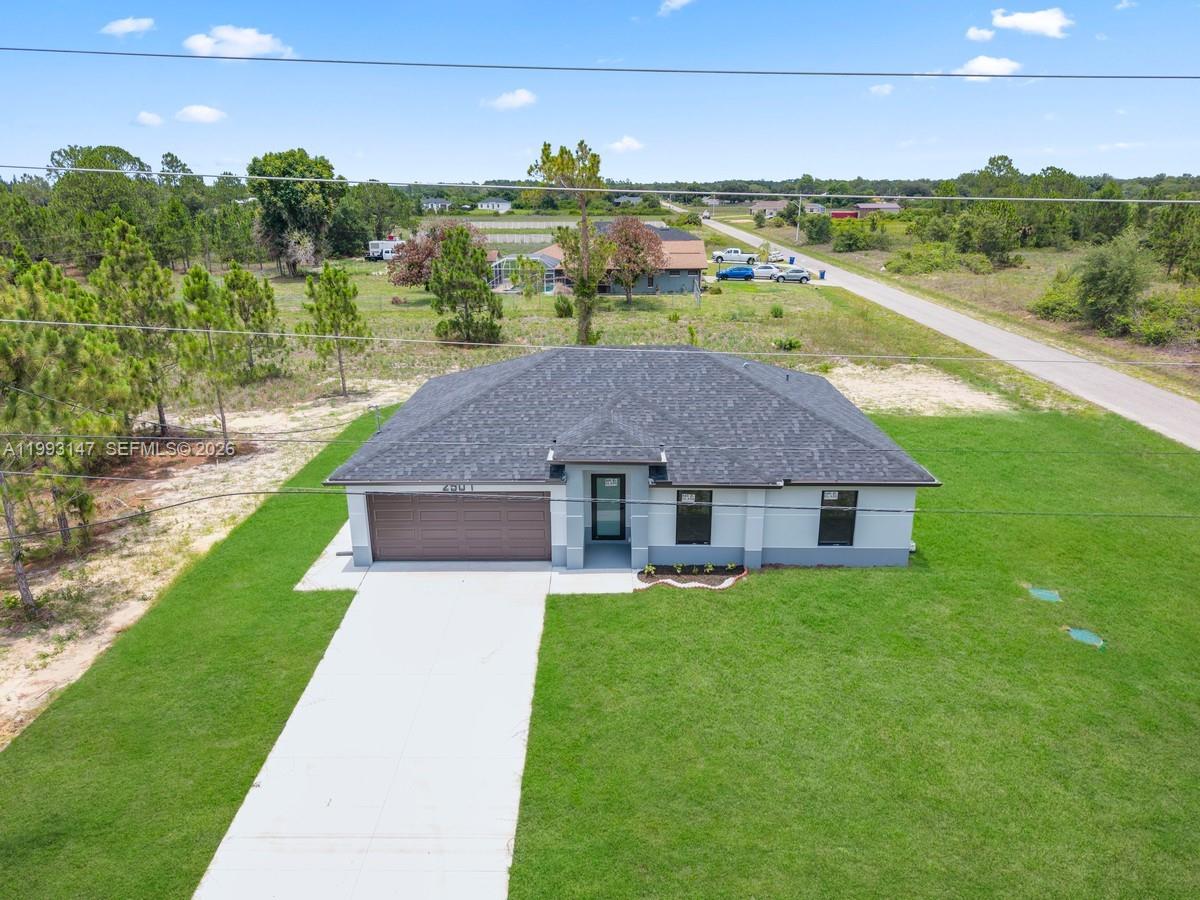 An aerial view shows a single-story house with a gray roof and a concrete driveway — 2507 E 15th ST, Lehigh Acres FL 33972, LEHIGH ACRES, FL