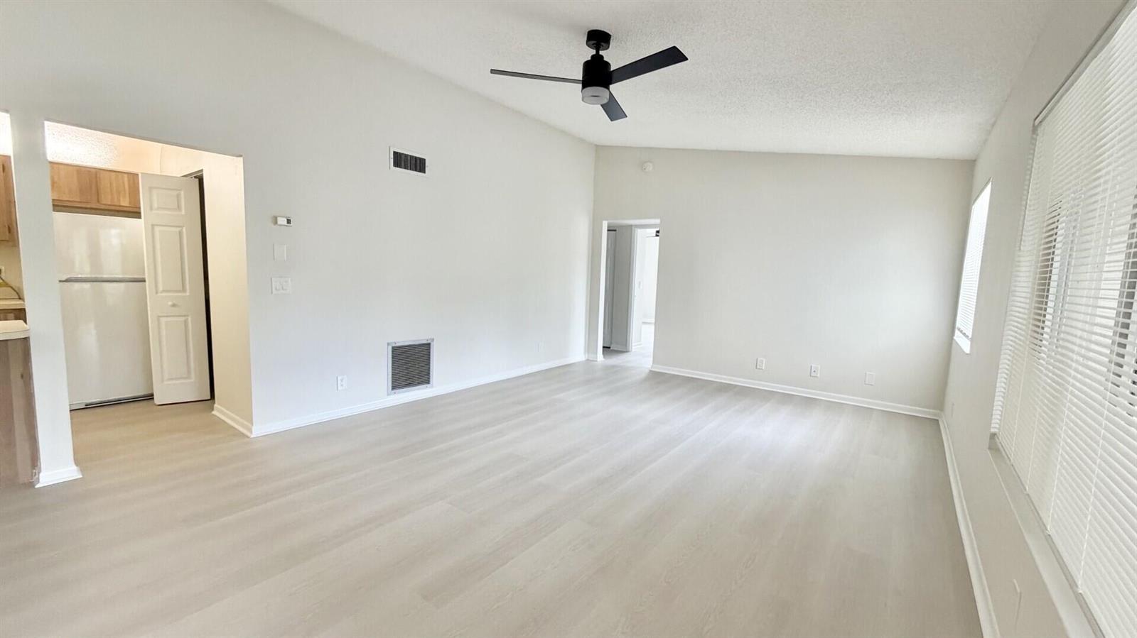 An empty living room features light-colored wood-look flooring, white walls, and a ceiling fan — 4969 Sable Pine Circle # D2, West Palm Beach FL 33417, WEST PALM BEACH, FL