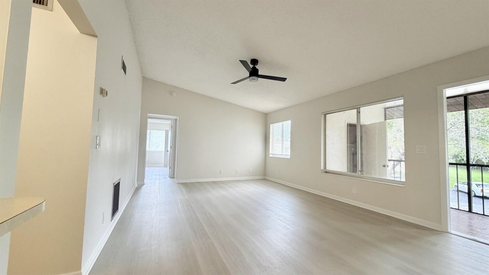 An empty living room features light-colored wood-look flooring, a ceiling fan, and a sliding door — 4969 Sable Pine Circle # D2, West Palm Beach FL 33417, WEST PALM BEACH, FL