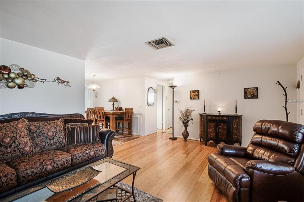 A living room with hardwood floors, a patterned sofa, a leather recliner, and dining area — 3802 MYNABIRD DRIVE, NEW PORT RICHEY, FL