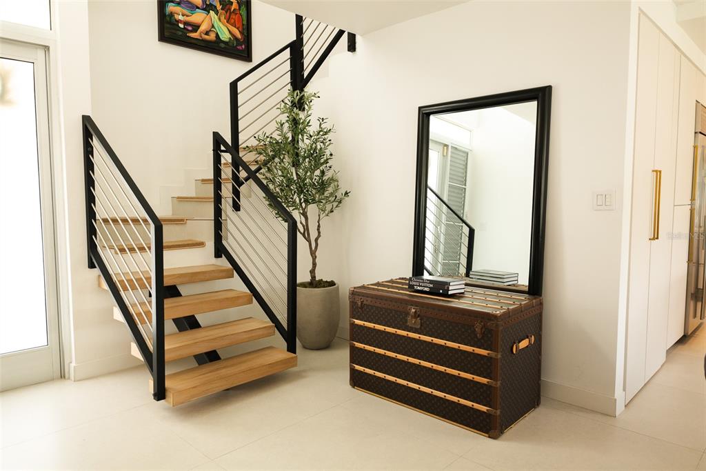 A modern entryway features a floating wooden staircase with black railings, a trunk, and mirror — 178 LOS ALTOS DE CIUDAD JARDÍN, GURABO, PR