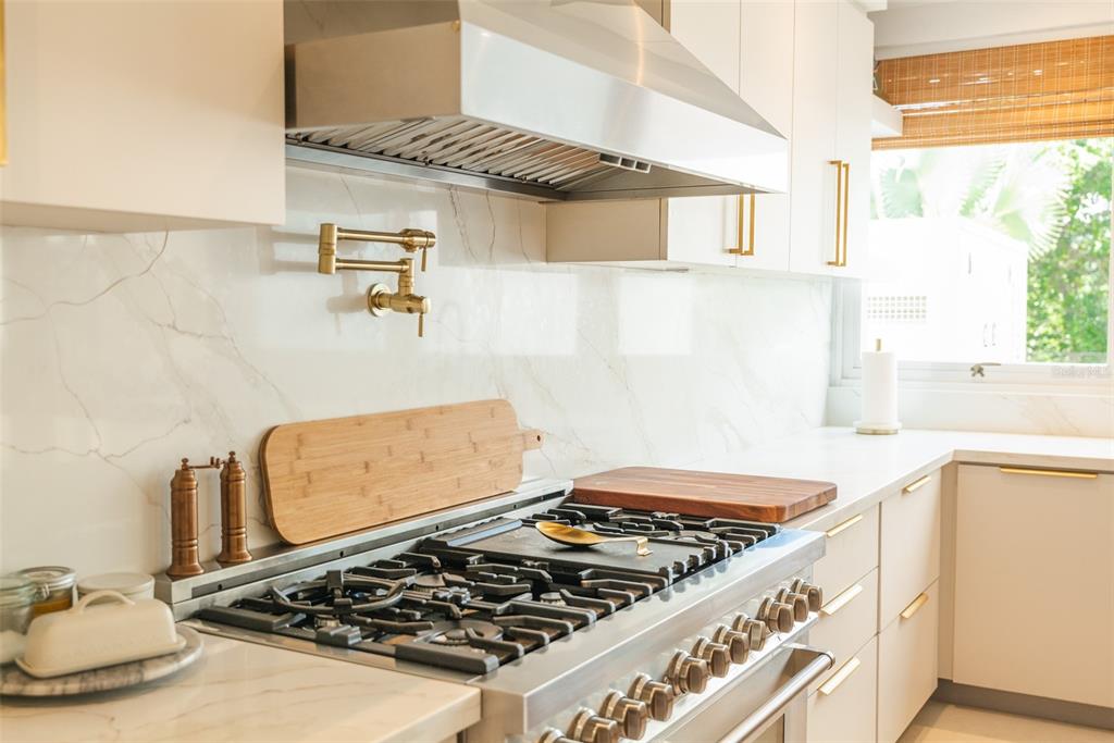 A kitchen features a stainless steel gas range, a gold pot filler, and marble-look backsplash — 178 LOS ALTOS DE CIUDAD JARDÍN, GURABO, PR