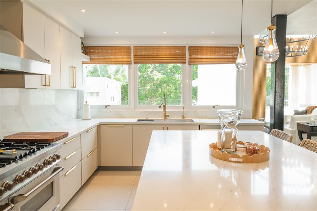 A modern kitchen features white cabinetry, marble countertops, a large island, and three windows — 178 LOS ALTOS DE CIUDAD JARDÍN, GURABO, PR