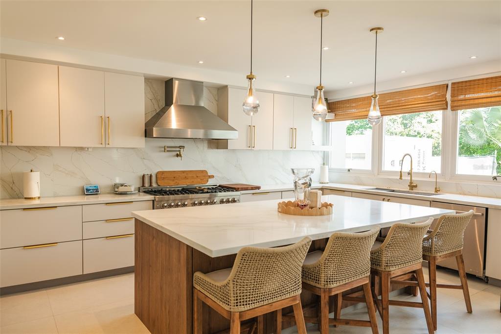 A modern kitchen features white cabinetry, a marble backsplash, and a large wooden island — 178 LOS ALTOS DE CIUDAD JARDÍN, GURABO, PR