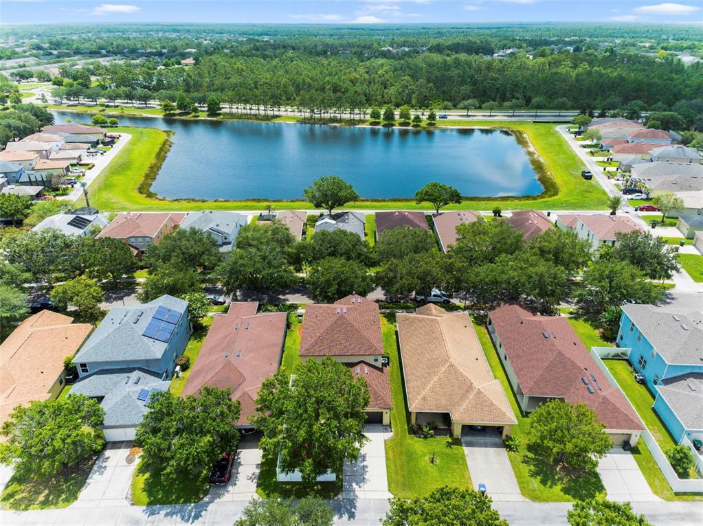 An aerial view shows a suburban neighborhood with houses bordering a large retention pond — 2254 ABEY BLANCO DRIVE, ORLANDO, FL