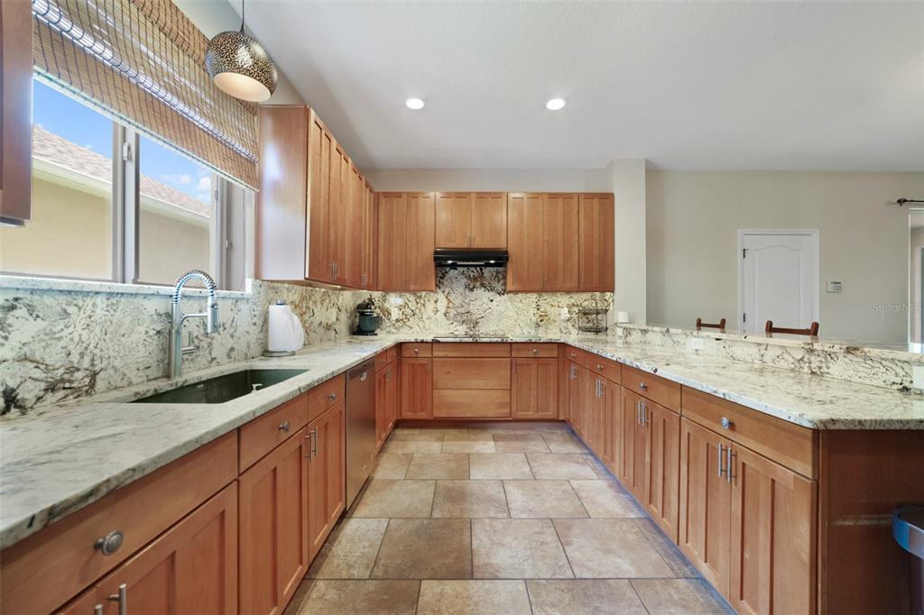 A kitchen features wood cabinets, granite countertops, a tile floor, and a stainless steel sink — 2254 ABEY BLANCO DRIVE, ORLANDO, FL